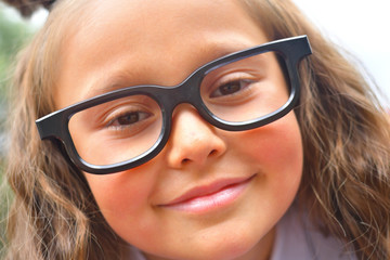 Portrait of beautiful young first-grader girl in eyeglasses. Focus on girls eyes