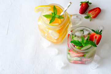 Summer refreshing iced drinks with orange, lemon, cucumber and strawberry on white background