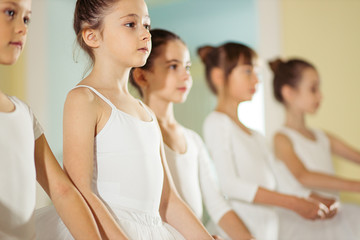 group of little caucasian ballerinas stand in a row and practice ballet together. pretty amazing dance performers in studio © alfa27