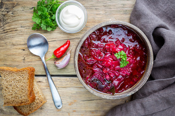 Traditional Ukrainian Russian vegetable beet soup, borscht on wooden background, top view