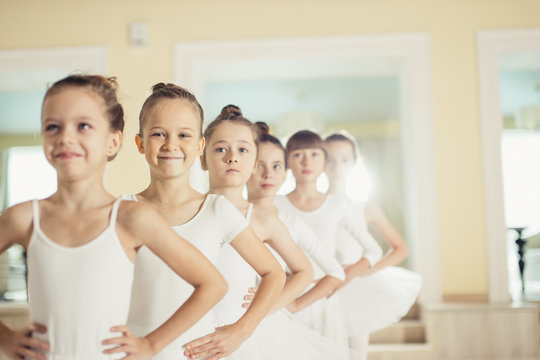 sweet caucasian little ballerinas wearing white tutu perdorming dance together, ballet concept