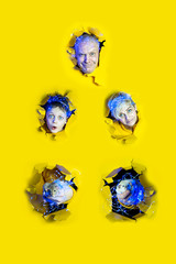 Surprised faces of people and rats in New Year's garlands peek out of holes in yellow paper. The large size of each portrait.