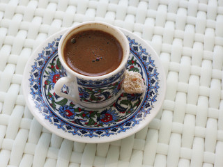 Turkish tea served in traditional glass with a saucer and tea spoon on dark background