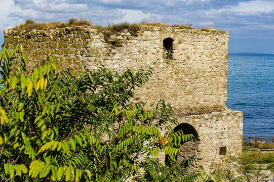 Medieval Genoese fortress on shore of Theodosius Bay in southern part of city. Close-up of fortification tower of Genoese fortress Kafa. Feodosia, Crimea, Russia, September, 2019: 