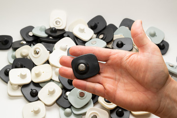 many multi-colored anti-theft sensor on a man’s male hand on a light background