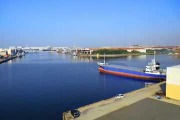 Fototapeta premium A Cargo Hold Japan Coastal Ship is moored at Industrial port surrounded by factory buildings on Osaka Bay,Japan.