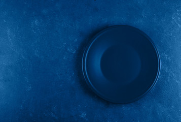 Empty plate on blue concrete background. Classic blue. Trend color of 2020 year. Top view with copy...
