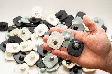 many multi-colored anti-theft sensor on a man’s male hand on a light background