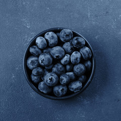 Bowl with blueberry on classic blue background. Top view. copy space, top view.