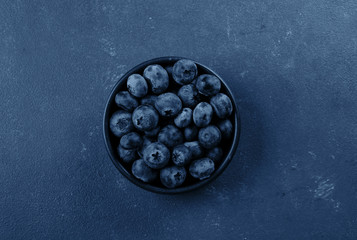 Bowl with blueberry on classic blue background. Top view. copy space, top view.