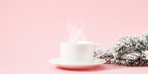 Winter or christmas pink cozy composition. Steaming cup coffee or hot drink, fir tree branches on light pink pastel background. Christmas, New Year, winter concept. Front view, copy space