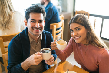 Portrait Of Happy Lovers With Coffee Cups At Cafe