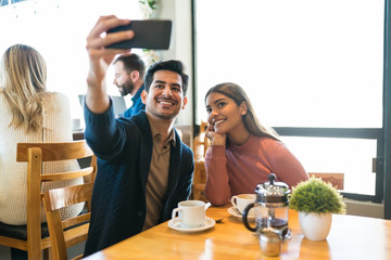 Couple Taking Selfie At Table In Cafe
