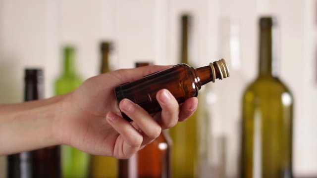young woman holding an empty glass liquor bottle. empty liquor bottles as a background