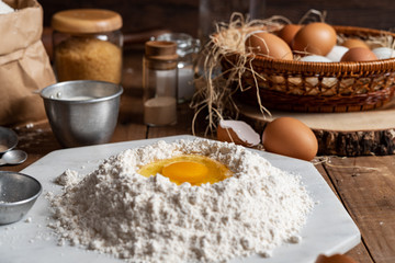 Flour with yolk egg and A lot of eggs put in the basket are placed on the wooden table for cooking something.