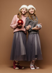 Cute happy twins with a baubles on brown background