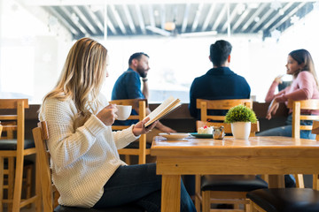 Woman Reading Book While Having Coffee At Cafe