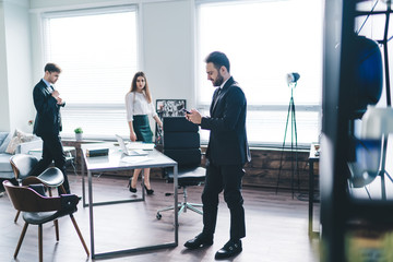 Coworkers moving to workplace next to colleague with smartphone