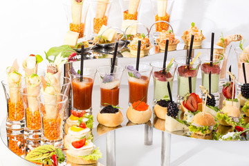 Snacks and canapes on the banquet table, closeup shot on a white background.