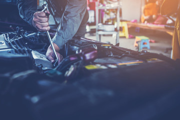 Fototapeta premium technician working on checking and service car in workshop garage; technician repair and maintenance engine of automobile in car service