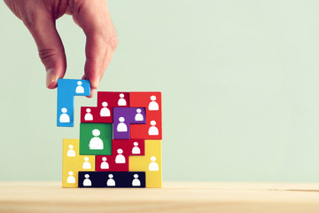 Business concept image of tangram puzzle blocks with people icons over wooden table, human...