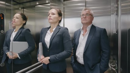 Confient business people exit leave modern metallic elevator, businessman and businesswoman stay calm keep silence during rising to office floor