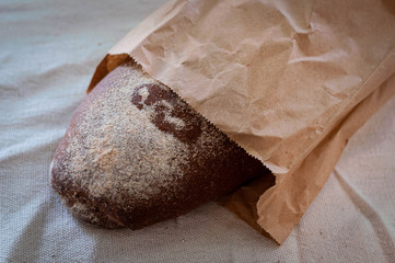 soft focus of loaf bread in brown craft recycling paper bag on rustic cloth at home