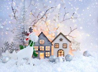 Fototapeta premium Christmas composition with decorative elk, huts and festive decorations оn the snow. Christmas or New Year greeting card.