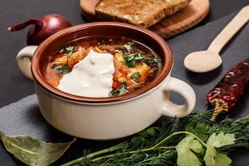 Ukrainian traditional borsch with rye bread on black background.