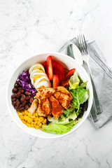 Top view of lunch bowl with chicken, egg, tomatoes, lettuce, corn, red beans, red cabbage. Clean food and dieting nutrition concept. Copy space, flat lay