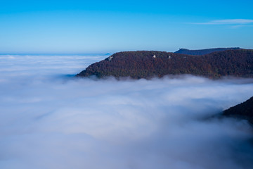 Germany, Breathtaking aerial view above endless fog clouds in valley of swabian jura nature landscape on sunny day with blue sky near stuttgart