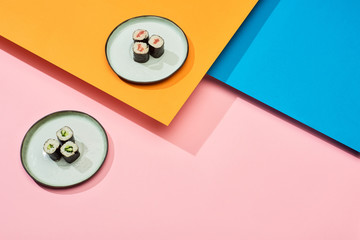 fresh maki with salmon and cucumber on blue, pink, orange surface © LIGHTFIELD STUDIOS