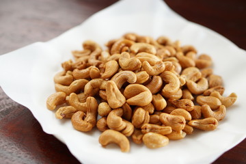 Angle view of fried cashew nuts in a dish with wood table.	