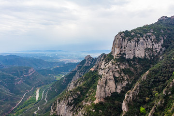 Fototapeta na wymiar Panoramic view of the mountains of the southern massif with the Hermitage of Cova hanging on its slope, Monistrol de Monserrat, Catalonia, Spain