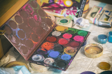 Top view of Paper, watercolors, paint brush and some art stuff on wooden table.