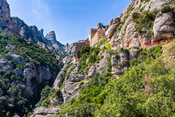 View of the tourist-religious complex of Montserrat hanging on a hillside of the mountain massif,...