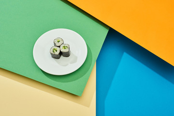 fresh maki with cucumber on plate on multicolored surface © LIGHTFIELD STUDIOS