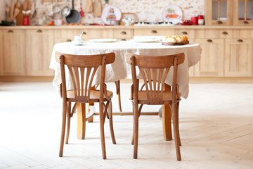 Stylish kitchen interior with wooden table and chairs. Wooden dining table for 4 people. Stylish kitchen interior. Rustic kitchen interior. Scandinavian dining room in cottage style. Eco furniture