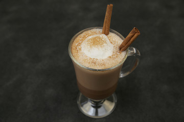 cup of cocoa, hot chocolate or coffee cappuccino with stick a cinnamon isolated on black background. Top view. Close-up.