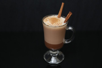 cup of cocoa, hot chocolate or coffee cappuccino with stick a cinnamon isolated on black background. With copy space for text.