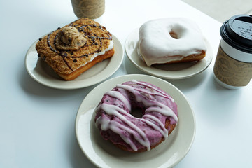 Cups of coffee served with vanilla glazed ,Chocolate chips cookie and blueberry donuts