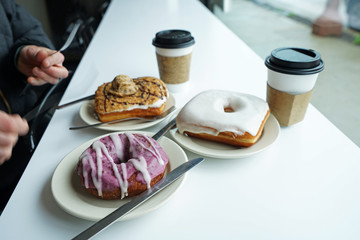 Cups of coffee served with vanilla glazed ,Chocolate chips cookie and blueberry donuts