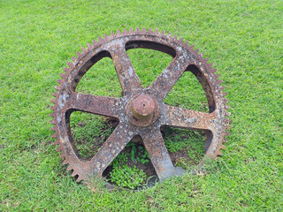 old rusty machinery wheel in green field background. Martinique island. French West Indies.