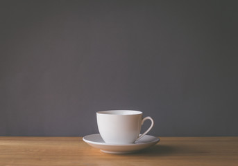 White coffee cup on wooden desk with grey background