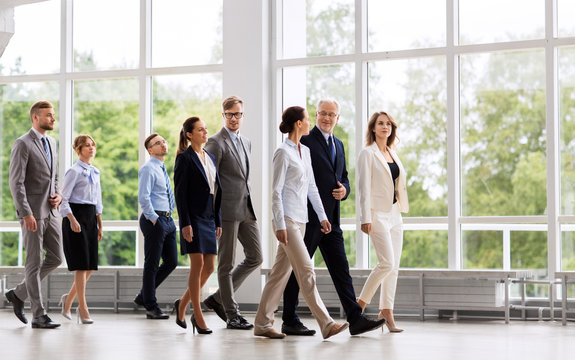 people, work and corporate concept - happy business team walking along office building and talking