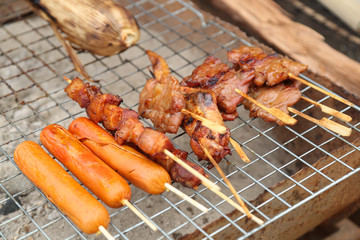 Sausage and belly pork and chicken wing and pork bbq on steel grating street food in Thailand