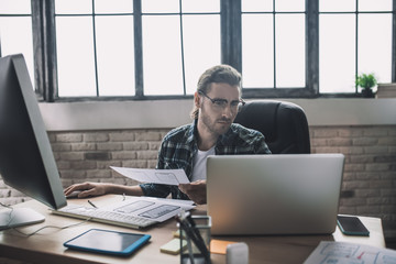 Young man in eyeglasses looking busy and involved