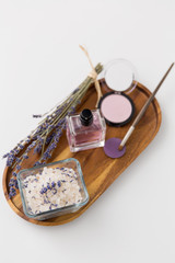 beauty, make up and wellness concept - sea salt, perfume, lavender and mineral cosmetics on wooden tray