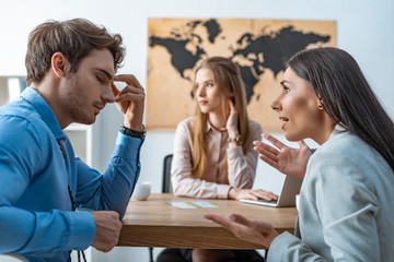 selective focus of quarreling couple of tourists near bored travel agent