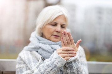 Senior woman with arthritis rubbing hands - obrazy, fototapety, plakaty